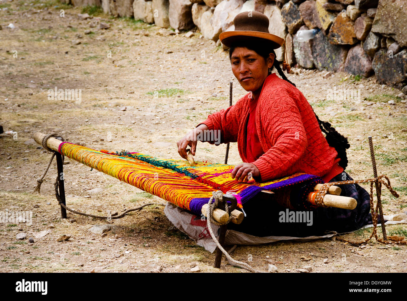 Woman in traditional dress weaving in the street, near Puno, Peru