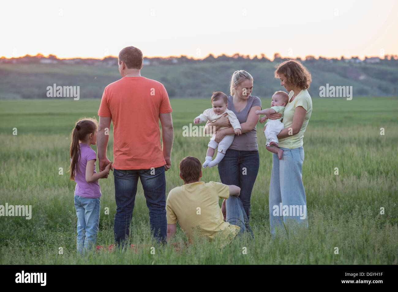 Two families relaxing in a field in a rural setting Stock Photo