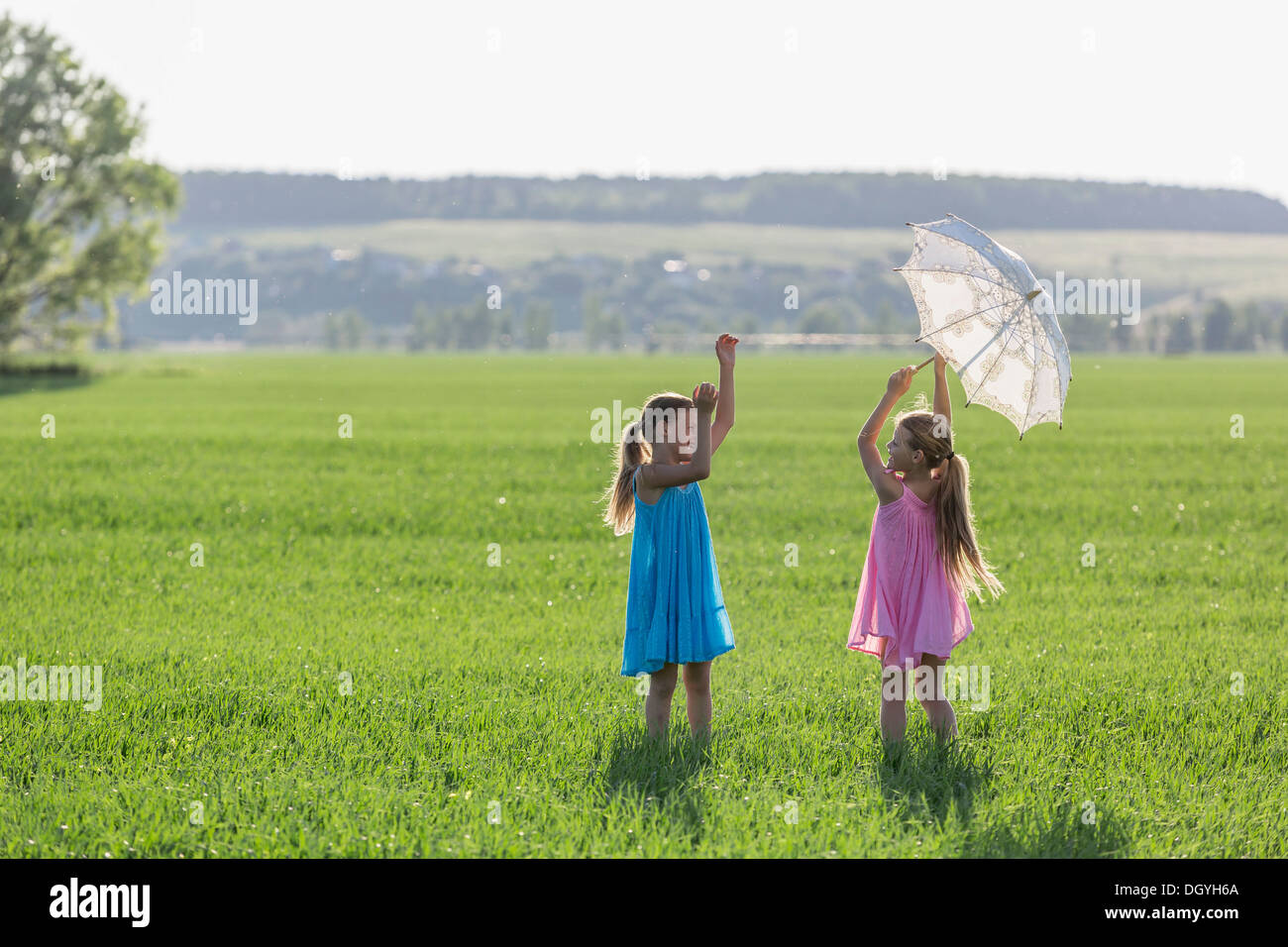 Twin sisters having fun while playing in sunny field Stock Photo
