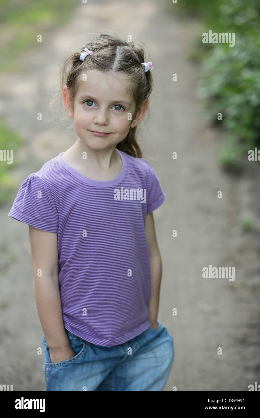 A young smiling girl standing on a dirt road Stock Photo