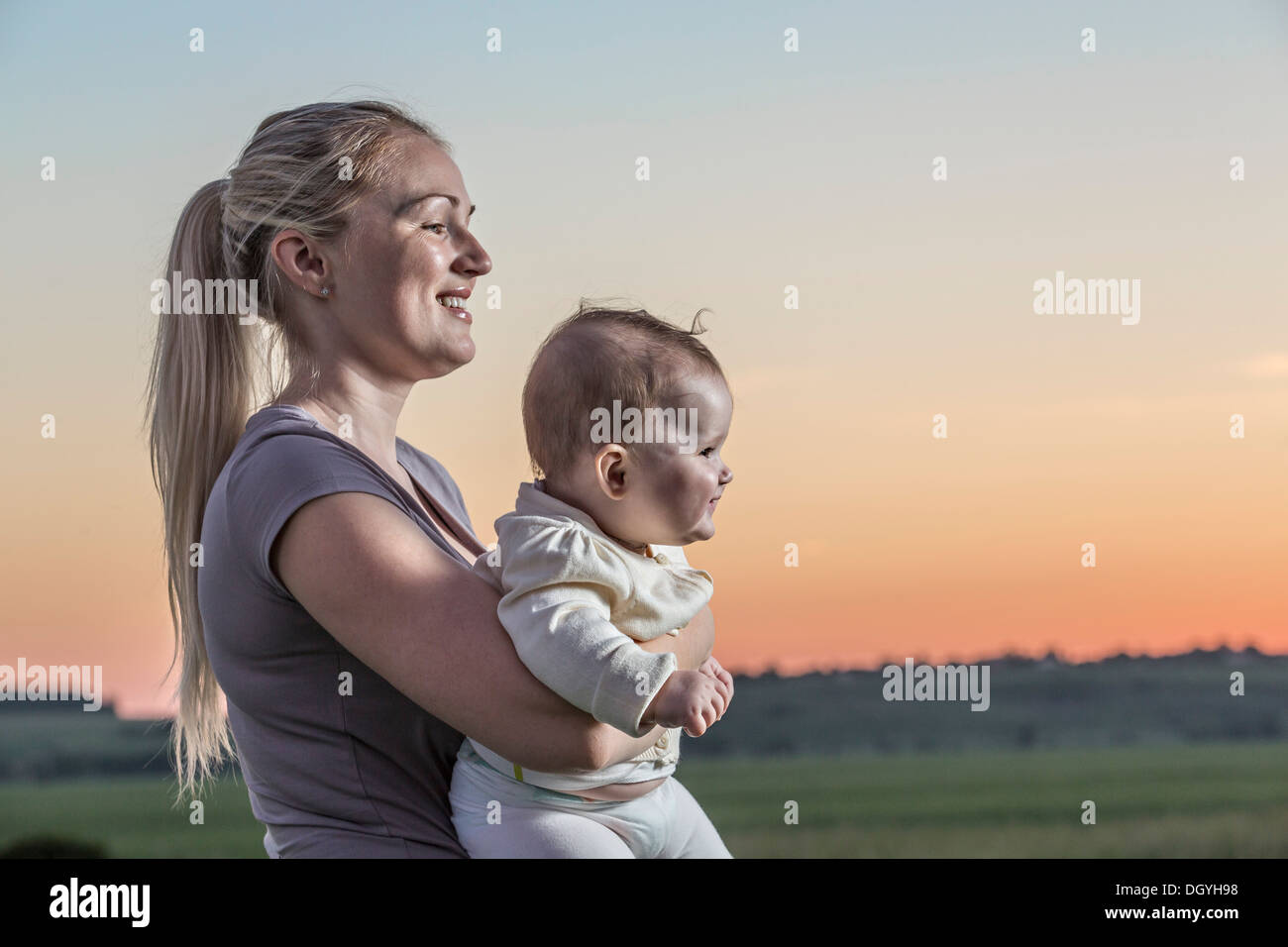 A laughing woman holding her baby in a natural setting Stock Photo