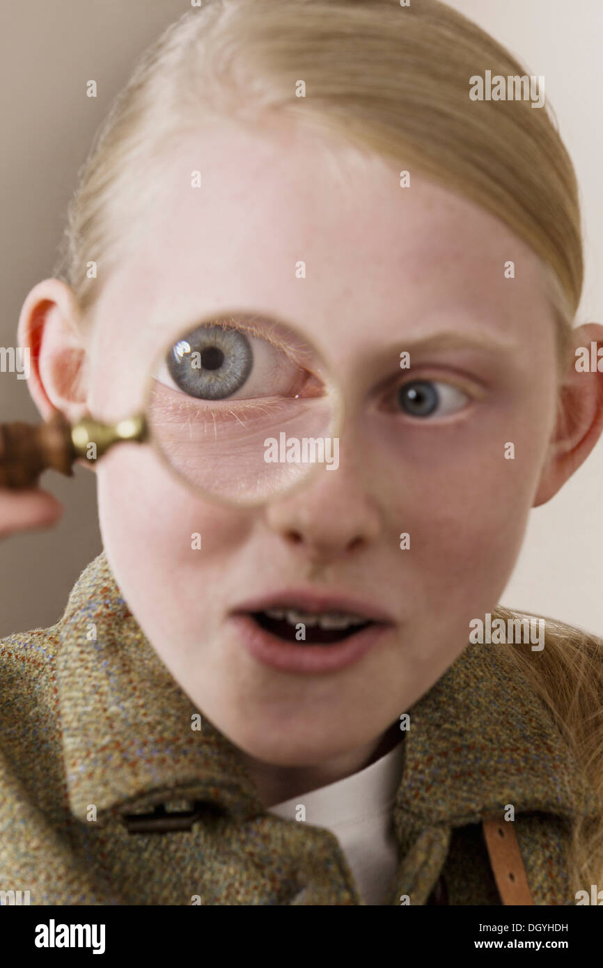 A girl looking surprised as she looks through a magnifying glass Stock Photo