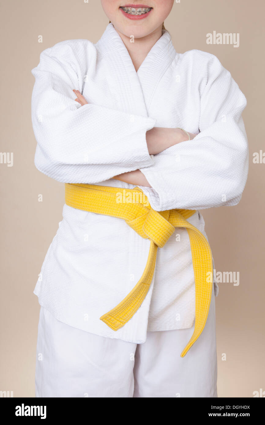 A smiling girl with arms crossed wearing martial arts uniform with yellow belt Stock Photo Alamy