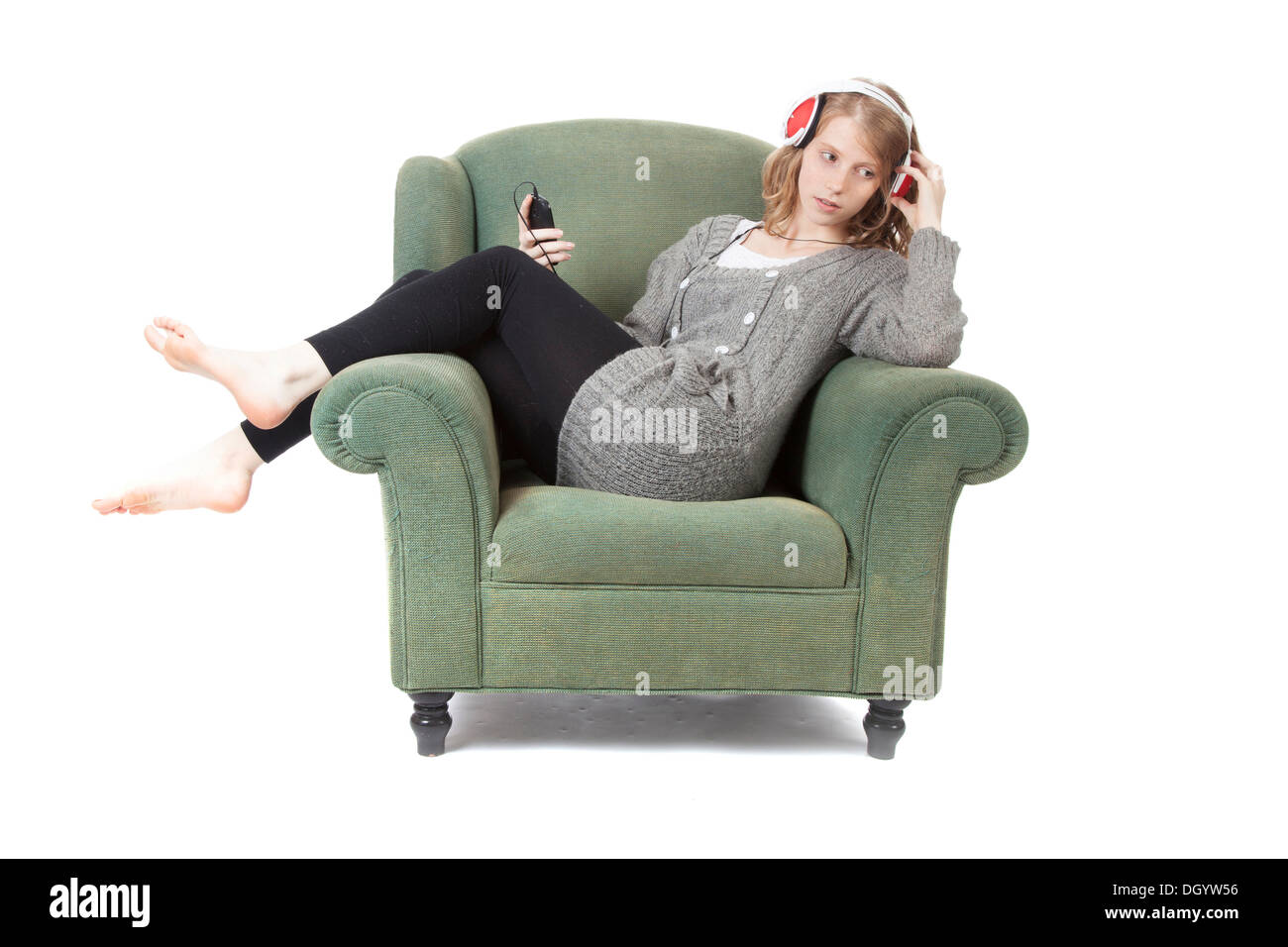 young pretty woman listening to music in armchair against white background Stock Photo