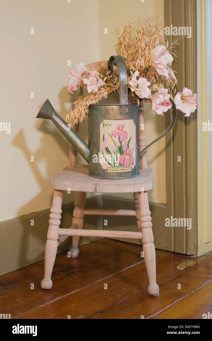 Antique Watering Can On Top Of A Small Chair In An Old