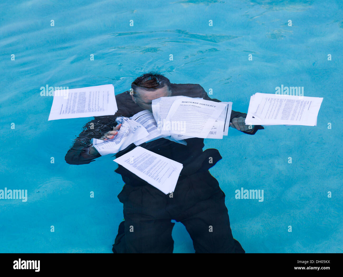 Businessman in suit sinking underwater in debt Stock Photo