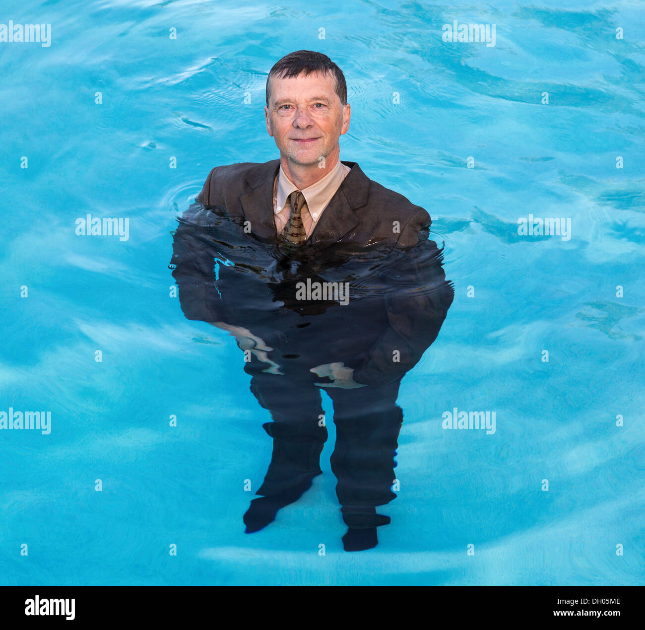 Middle aged / senior businessman in suit up to waist in water - keeping head above water concept Stock Photo