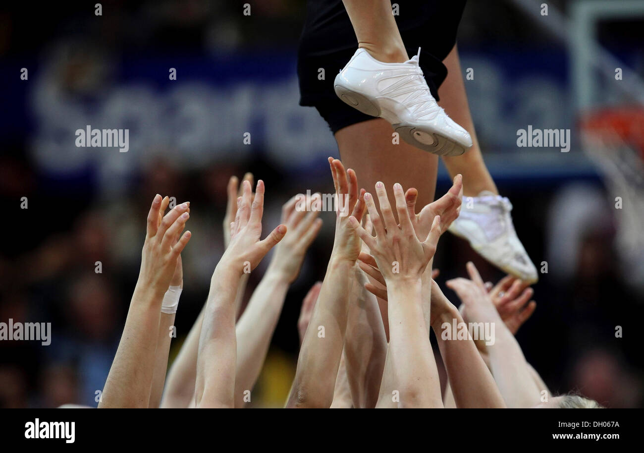 Cheerleaders stretching out their hands to support a cheerleader above Stock Photo