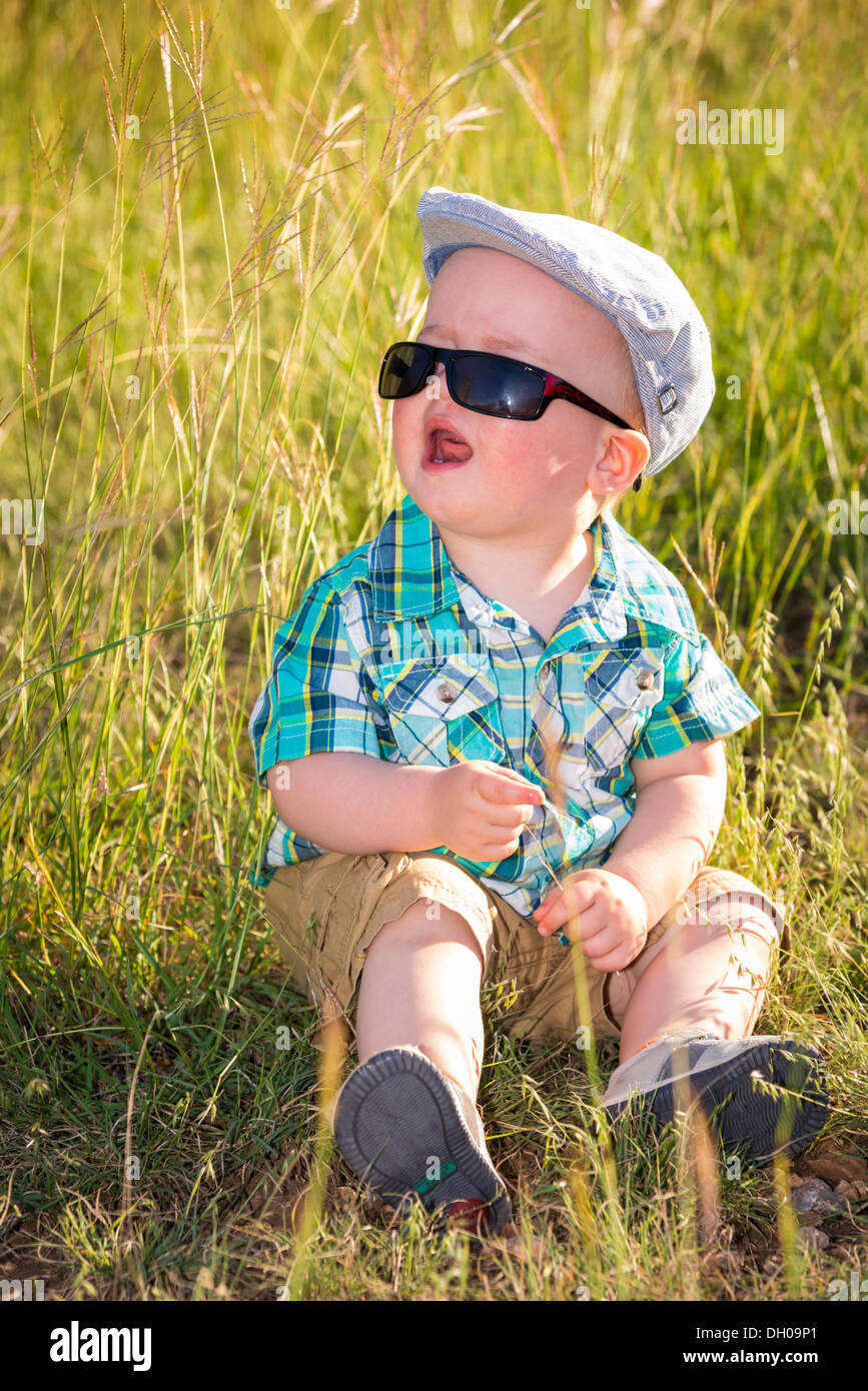 Young toddler boy with sunglasses sitting in tall grass crying Stock Photo  - Alamy