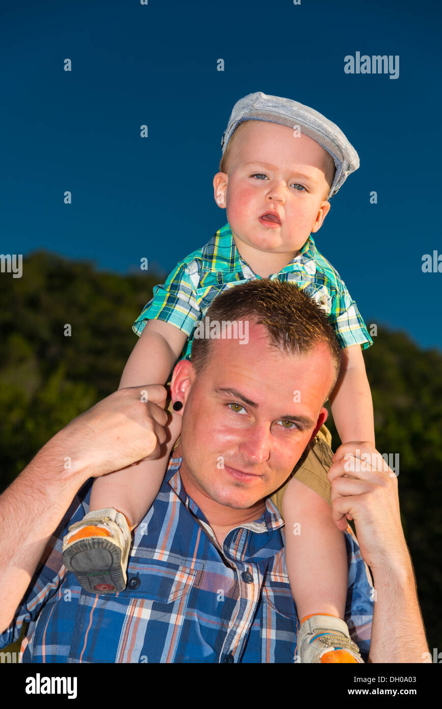 young male child sitting on the shoulders of his father enjoying the ride. Stock Photo