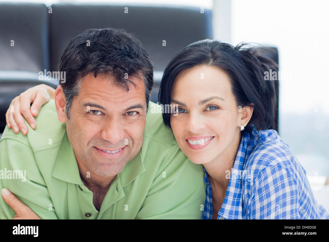 Hispanic couple smiling in living room Stock Photo