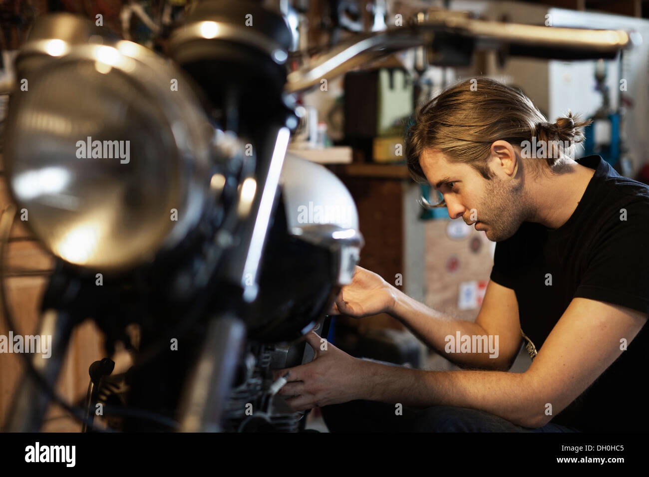 Caucasian mechanic working on motorcycle Stock Photo