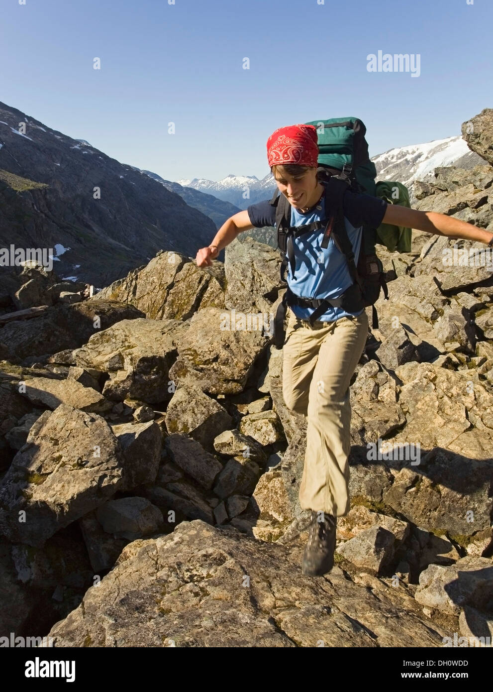 Young woman jumping, hiking, backpacking, hiker, legendary GOLDEN STAIRS of Chilkoot Trail, Pass, view into Taja River Valley, Stock Photo