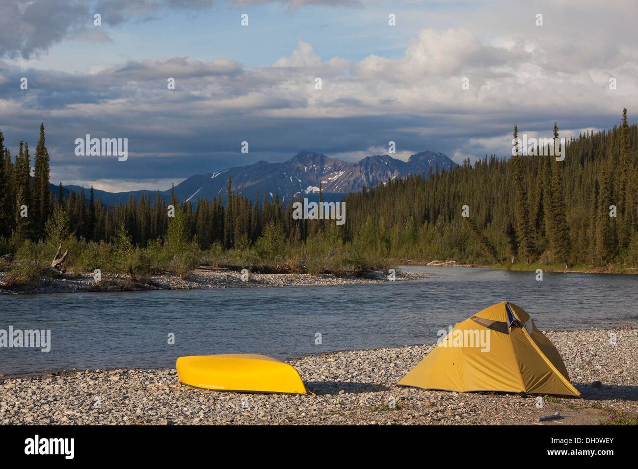 Camp on gravel bar, tent and canoe, Pelly Mountains behind, upper Liard River, Yukon Territory, Yukon Territory, Canada Stock Photo