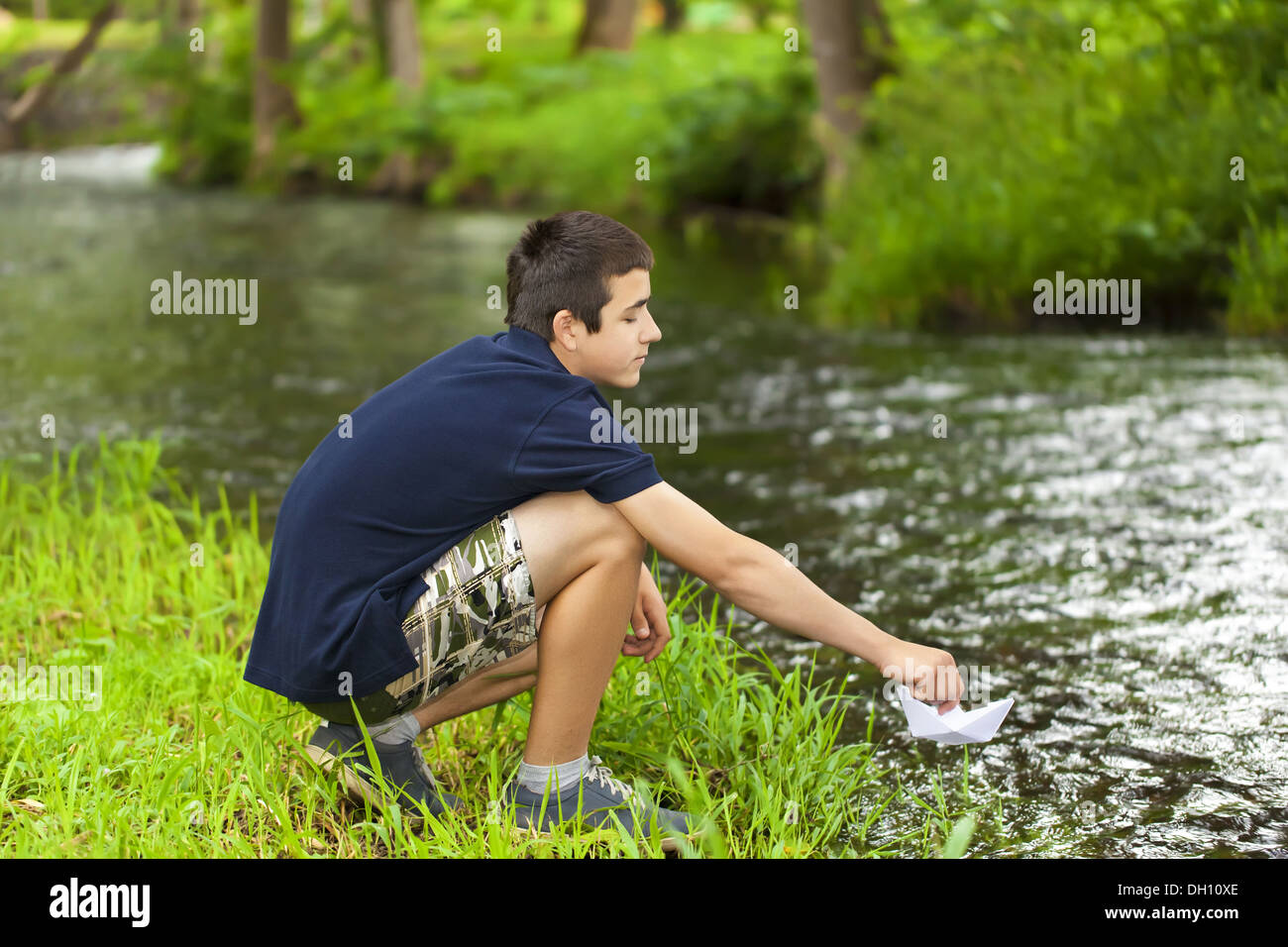 Boy with paper boat near the river Stock Photo