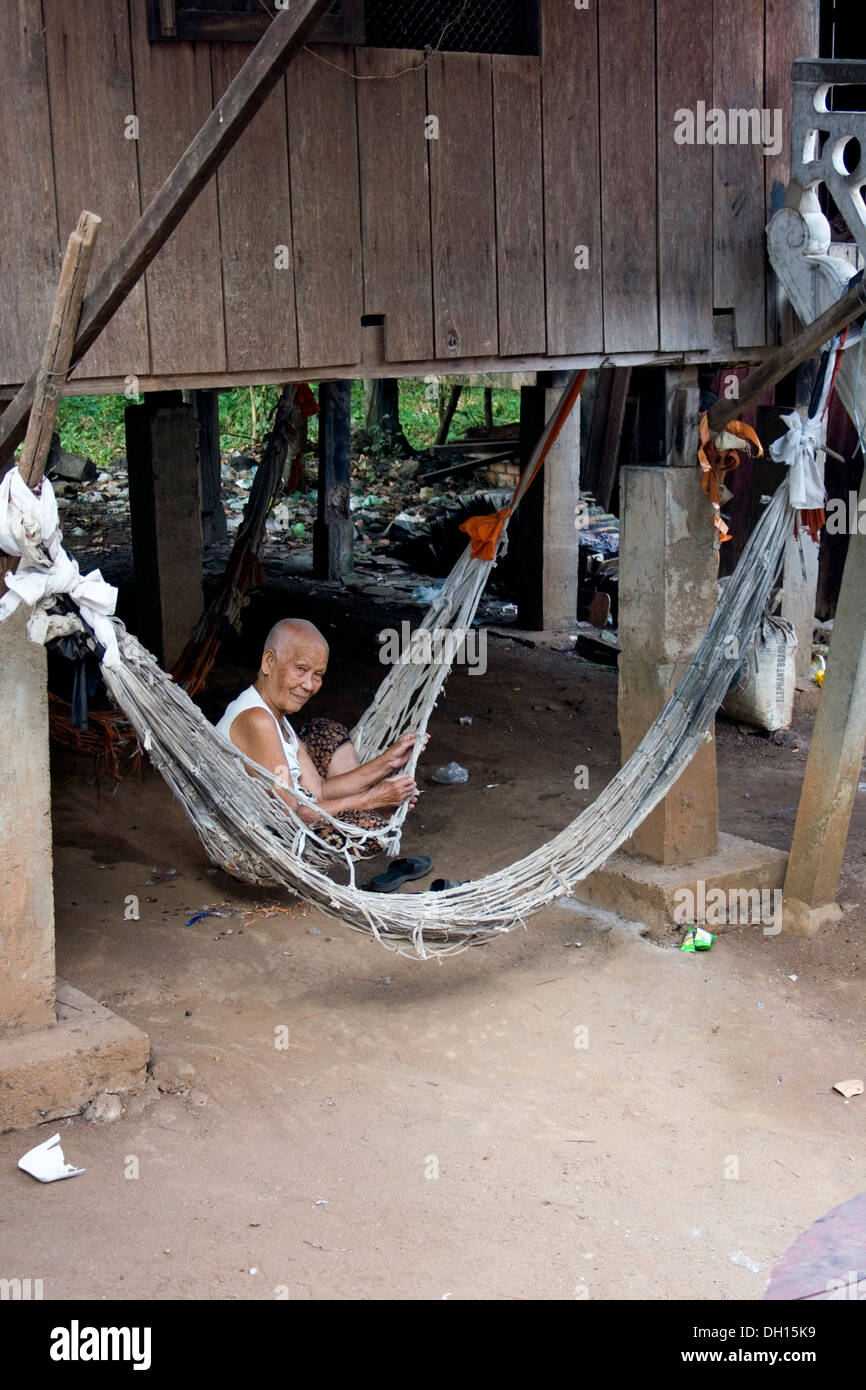 A Buddhist laywoman is relaxing under her wooden home at Boeng Kok temple in Kampong Cham, Cambodia. Stock Photo