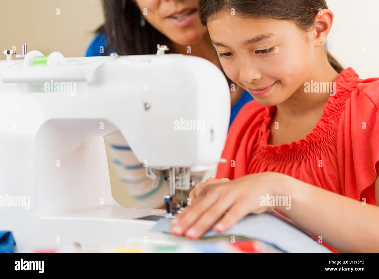 Mother teaching girl to use sewing machine Stock Photo
