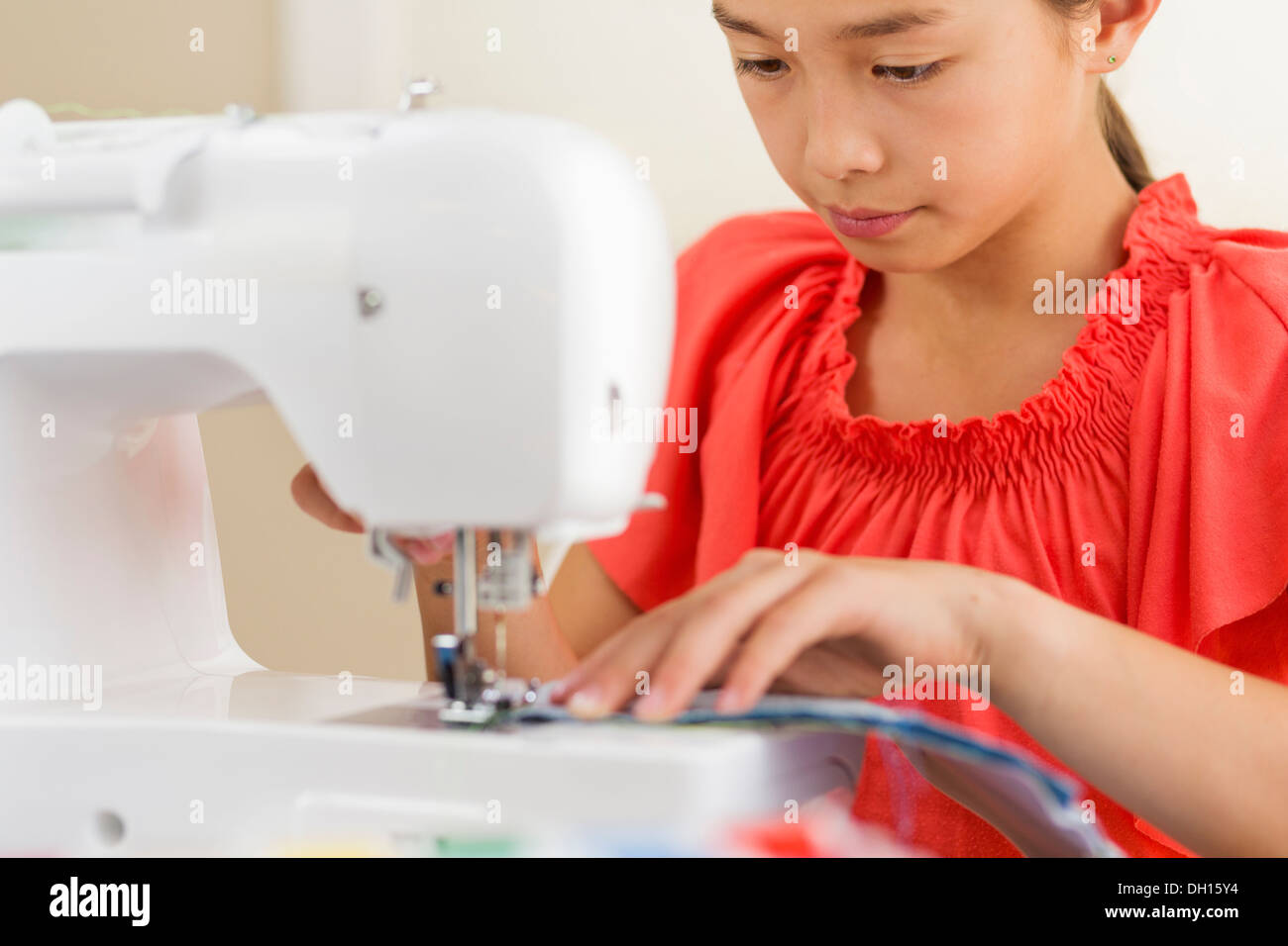 Mixed race girl using sewing machine Stock Photo
