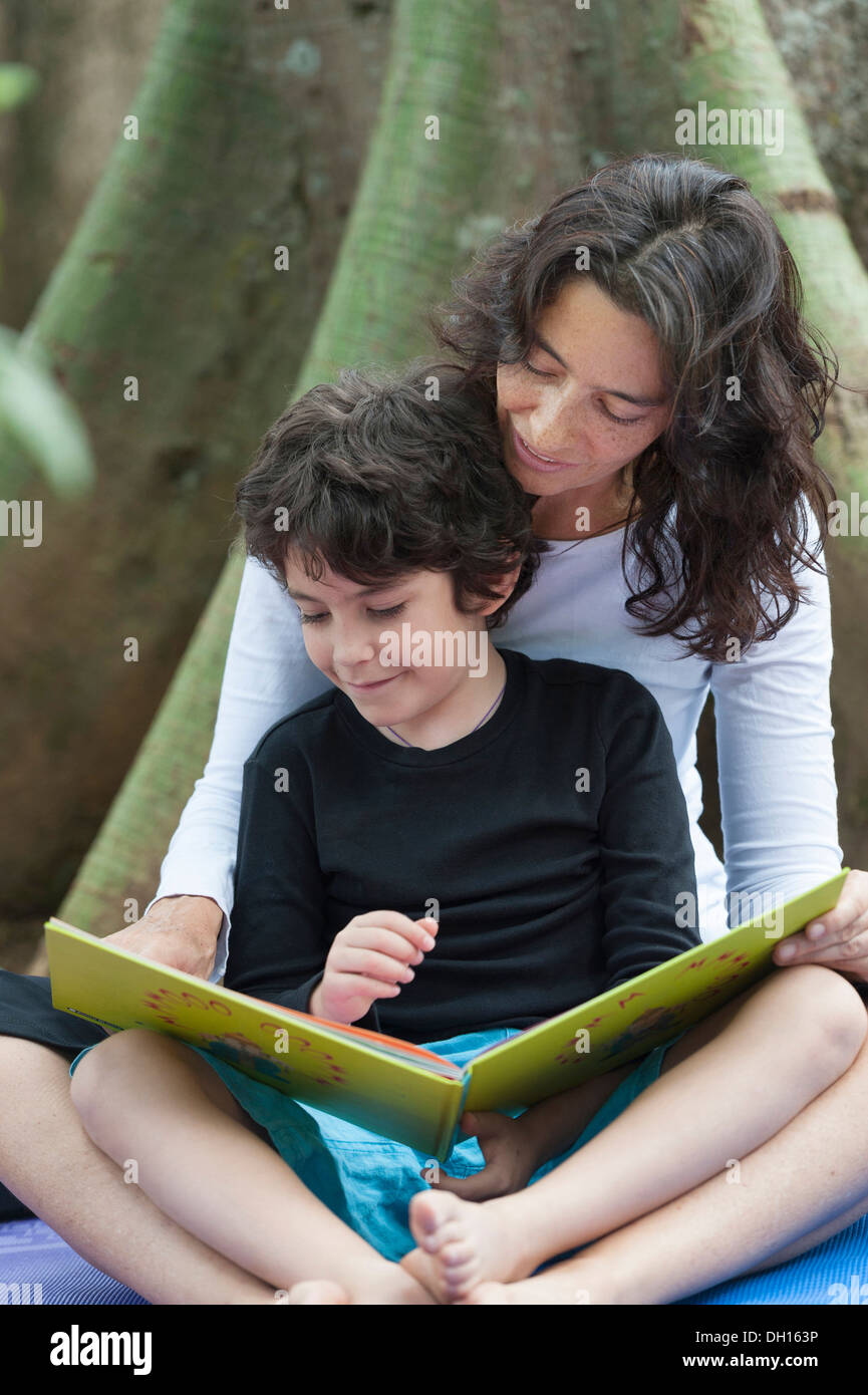 Hispanic mother and son reading outdoors Stock Photo