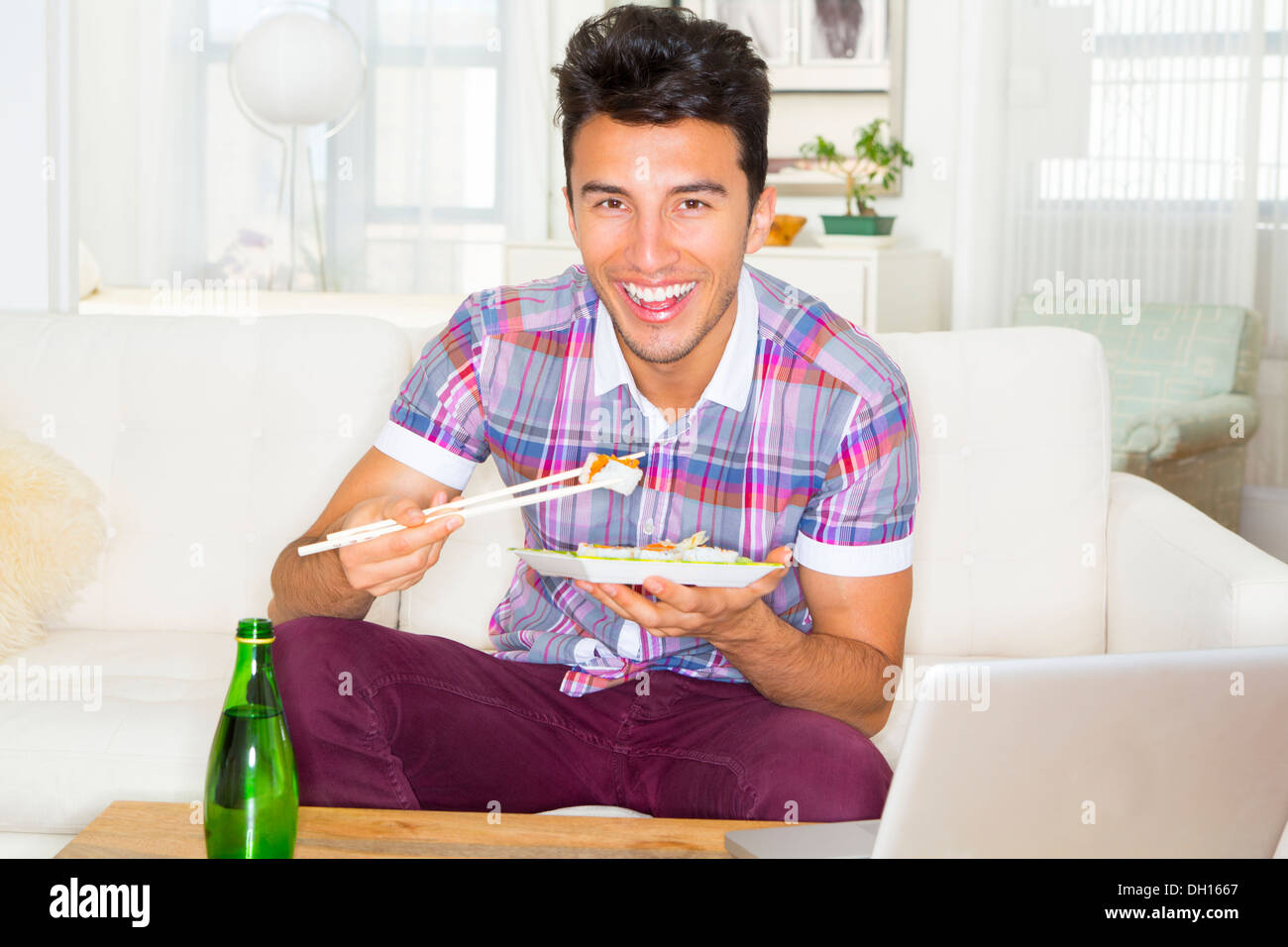 Mixed race teenager eating sushi on sofa Stock Photo