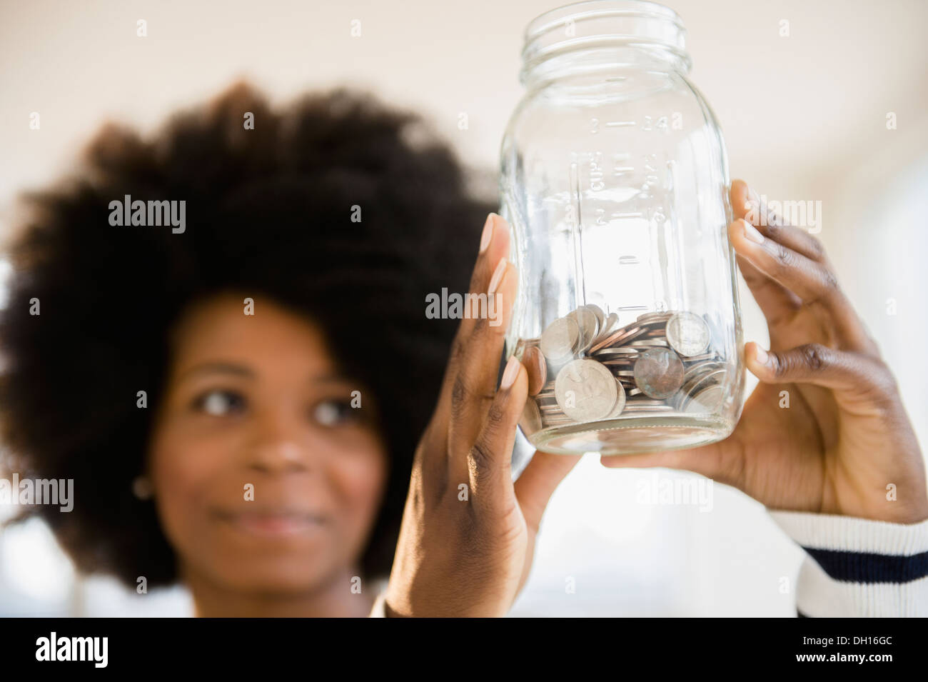 Mixed race woman holding jar of change Stock Photo