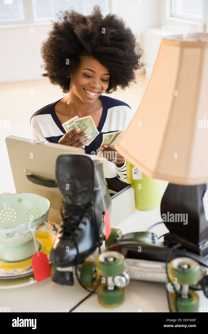 Mixed race woman counting money from yard sale Stock Photo