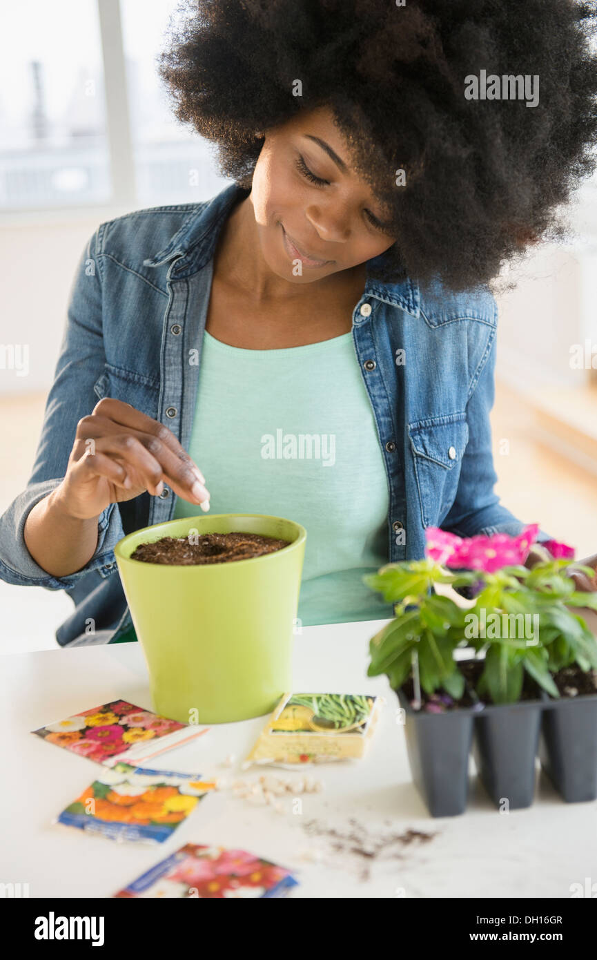 Mixed race woman planting flowers and seeds Stock Photo