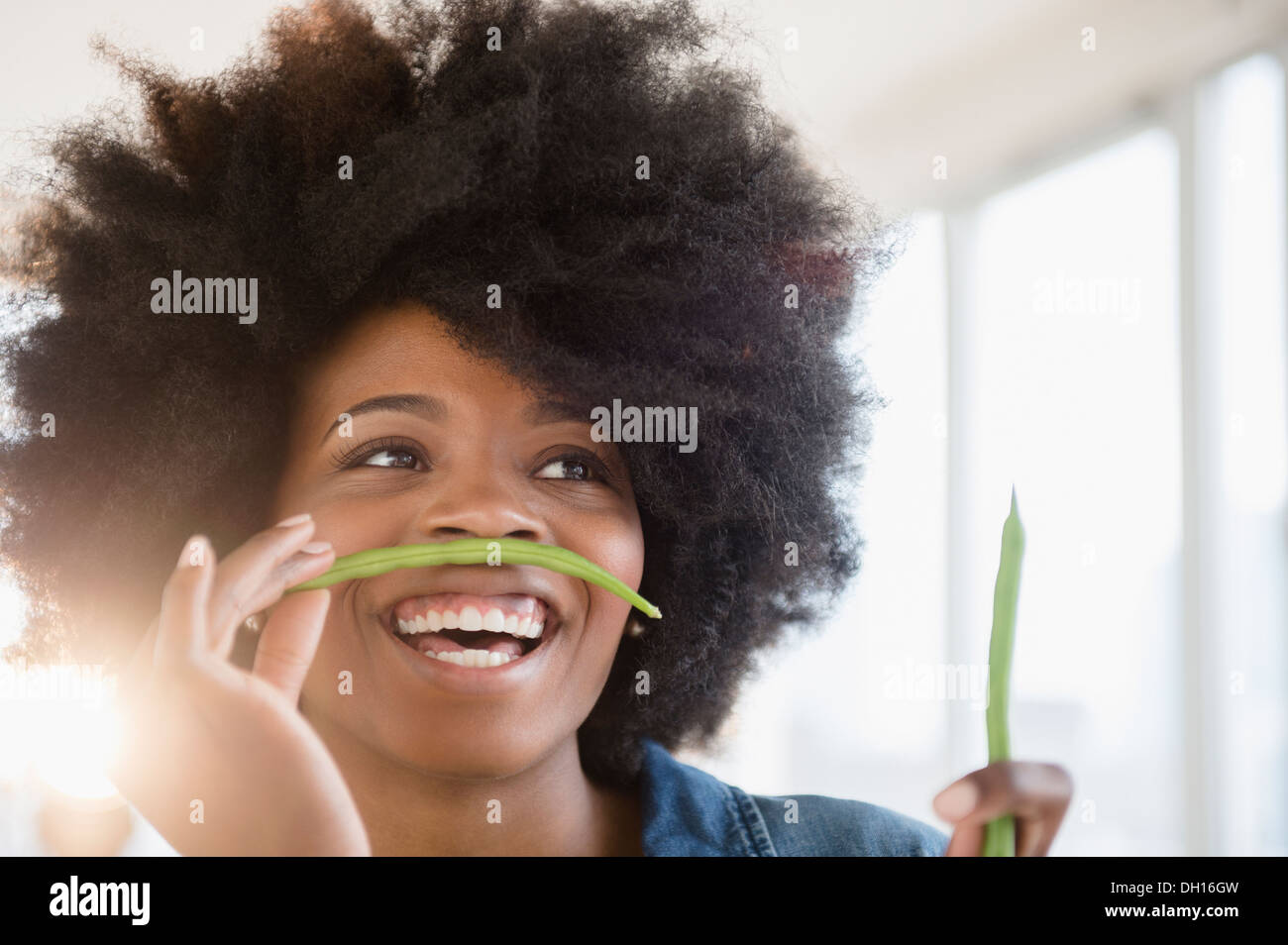 Mixed race woman playing with green beans Stock Photo
