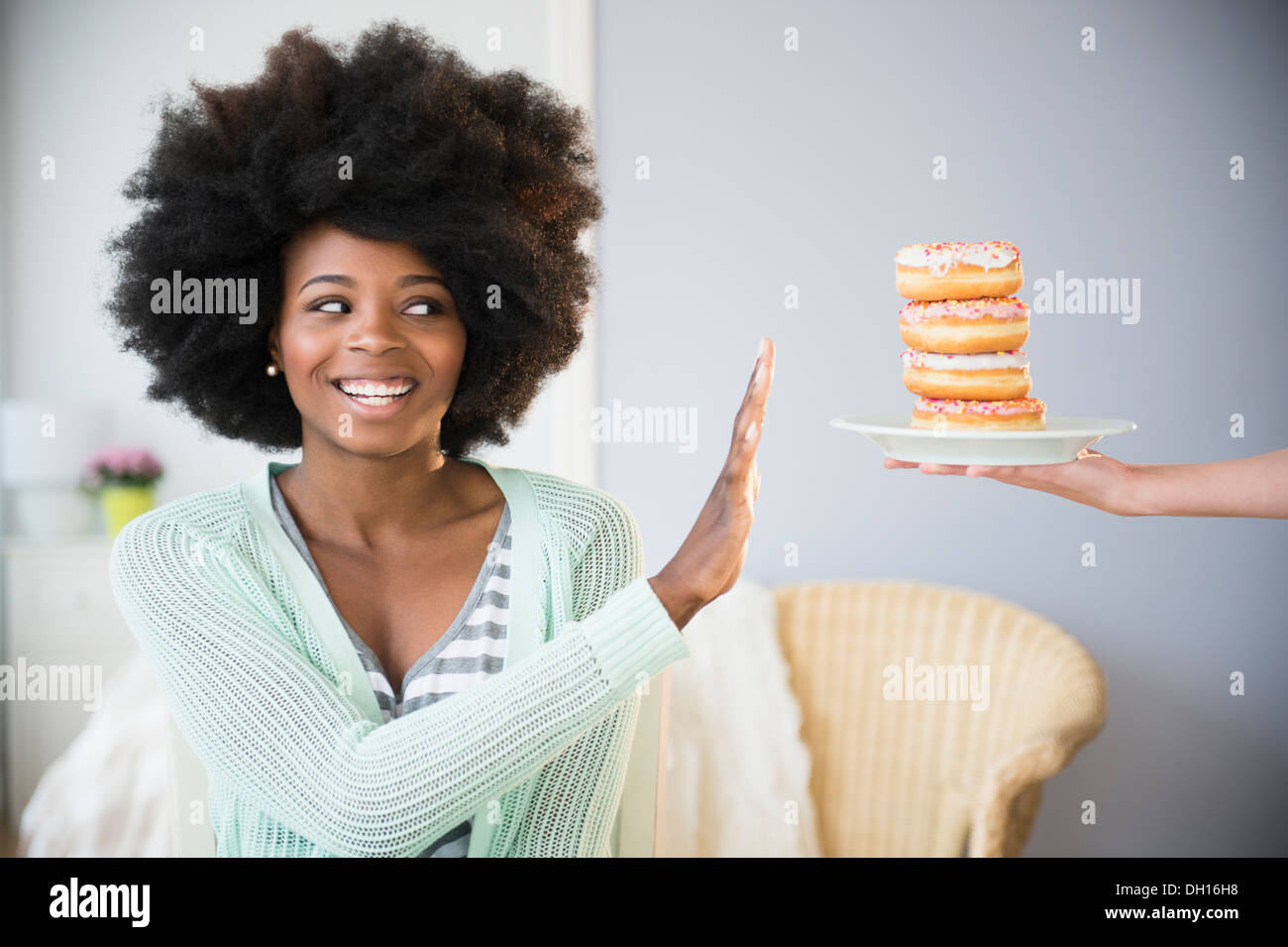 Mixed race woman refusing donuts Stock Photo