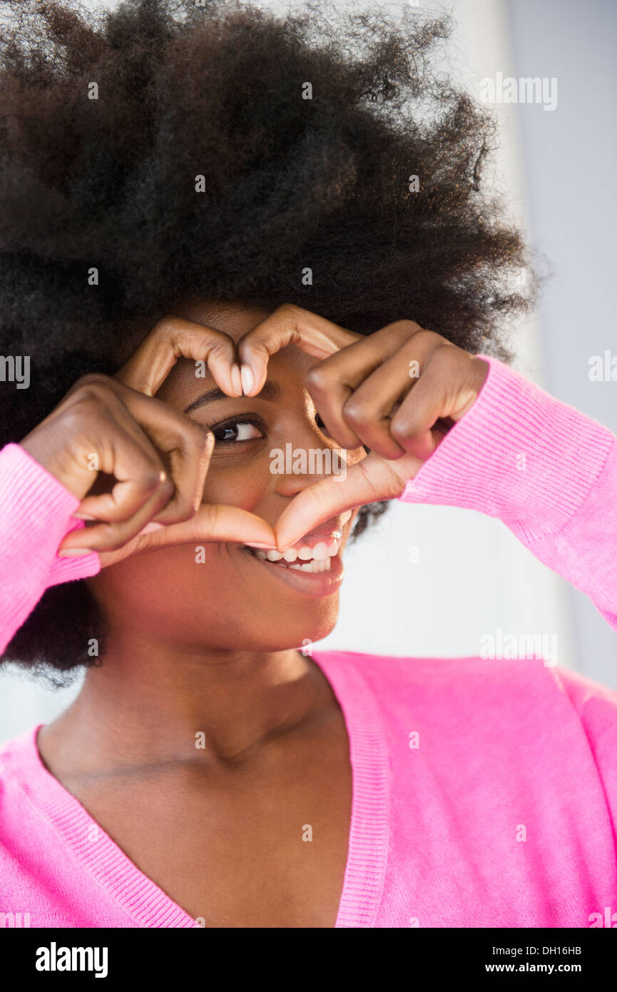 Mixed race woman making heart-shape with fingers Stock Photo