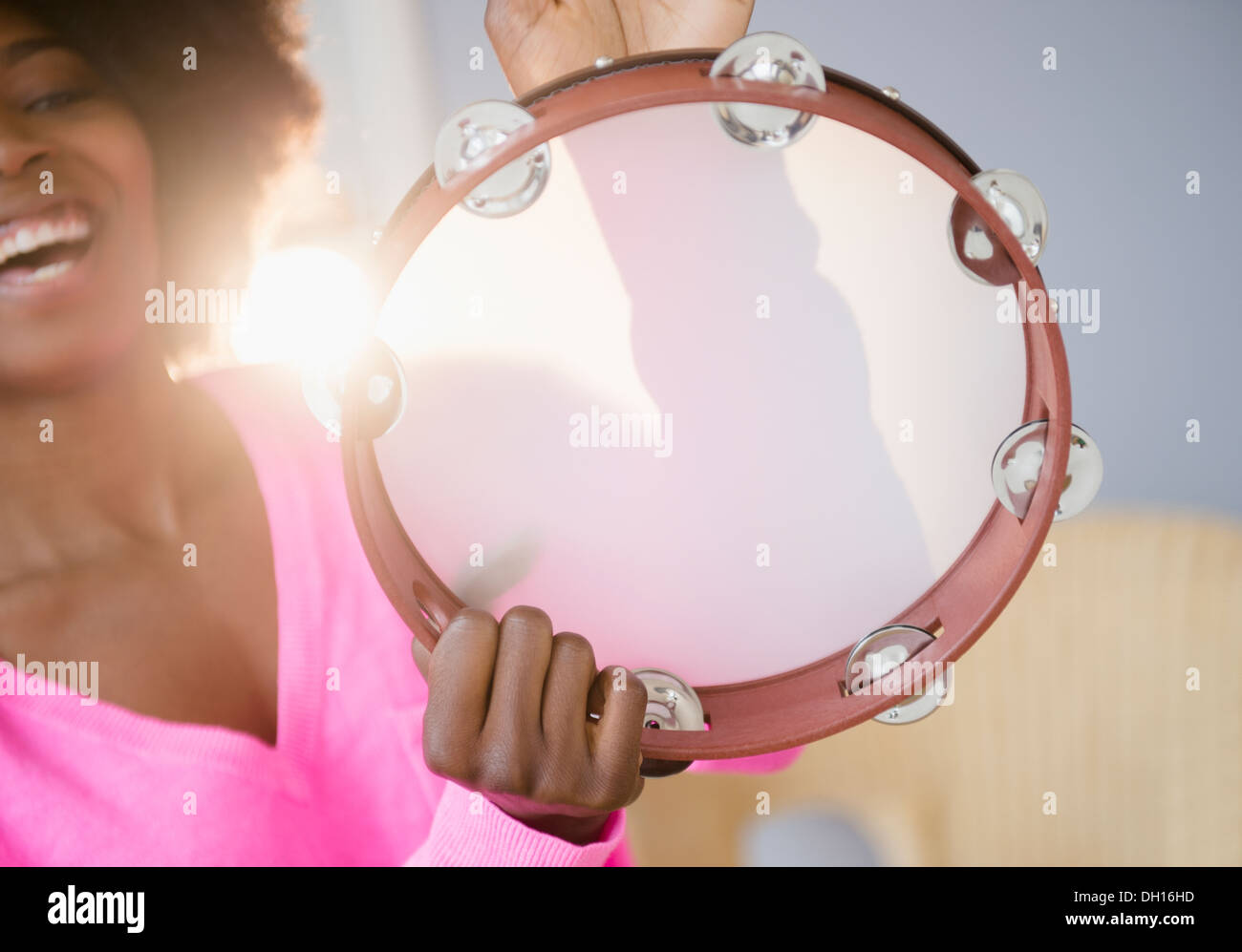 Mixed race woman playing tambourine Stock Photo