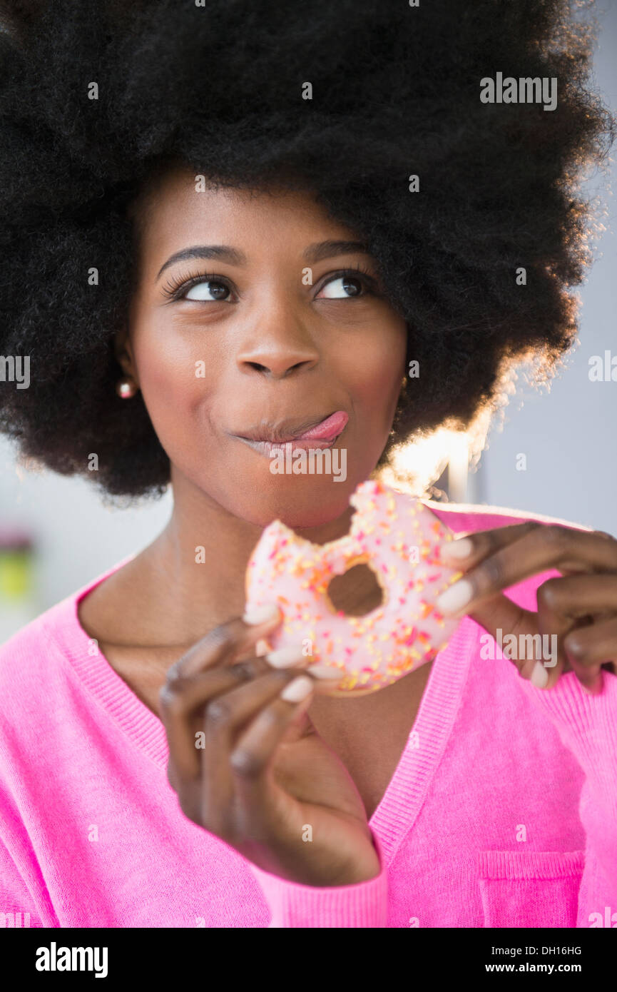 Mixed race woman eating donut Stock Photo
