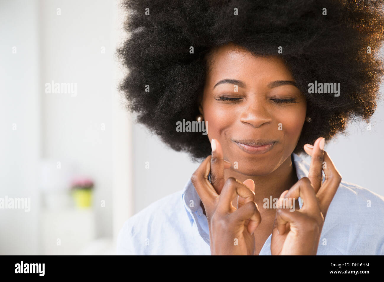 Mixed race woman crossing her fingers Stock Photo