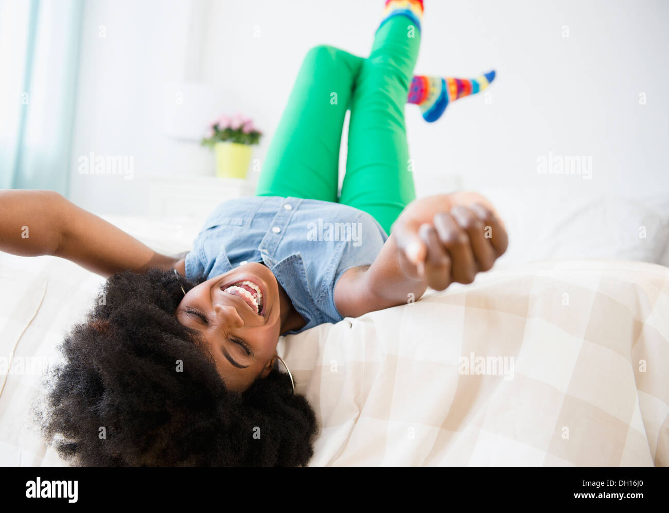 Mixed race woman smiling on bed Stock Photo