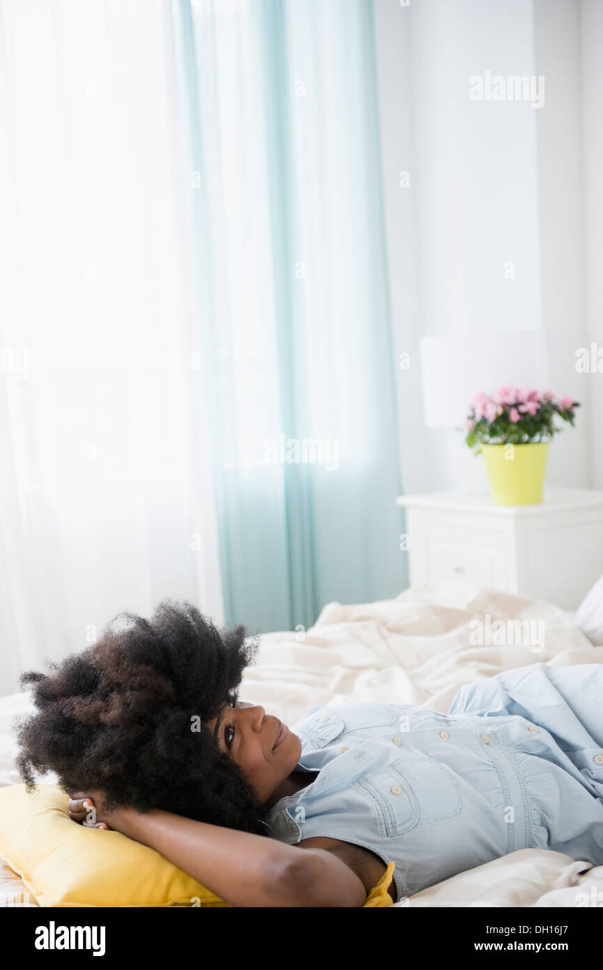 Mixed race woman laying on bed Stock Photo