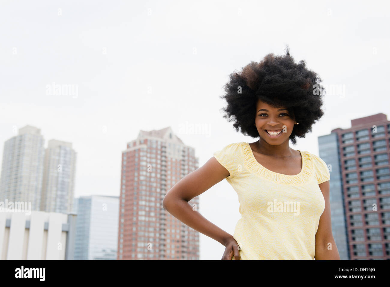 Mixed race woman smiling on urban rooftop Stock Photo
