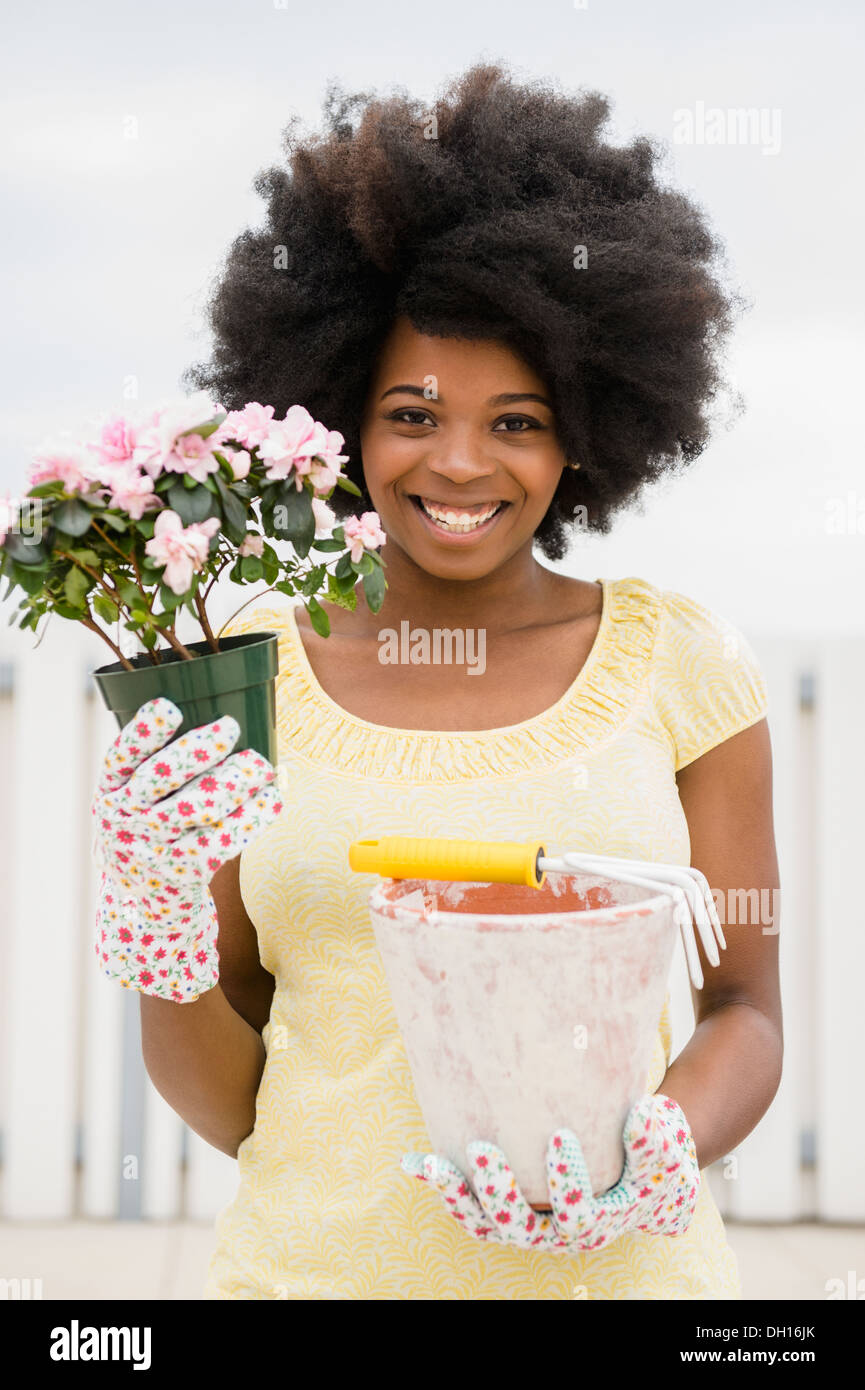 Mixed race woman holding flower and flowerpot Stock Photo