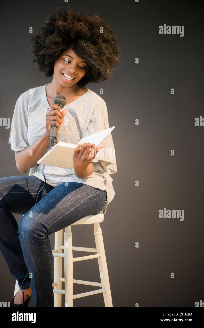 Mixed race woman doing poetry reading on stage Stock Photo
