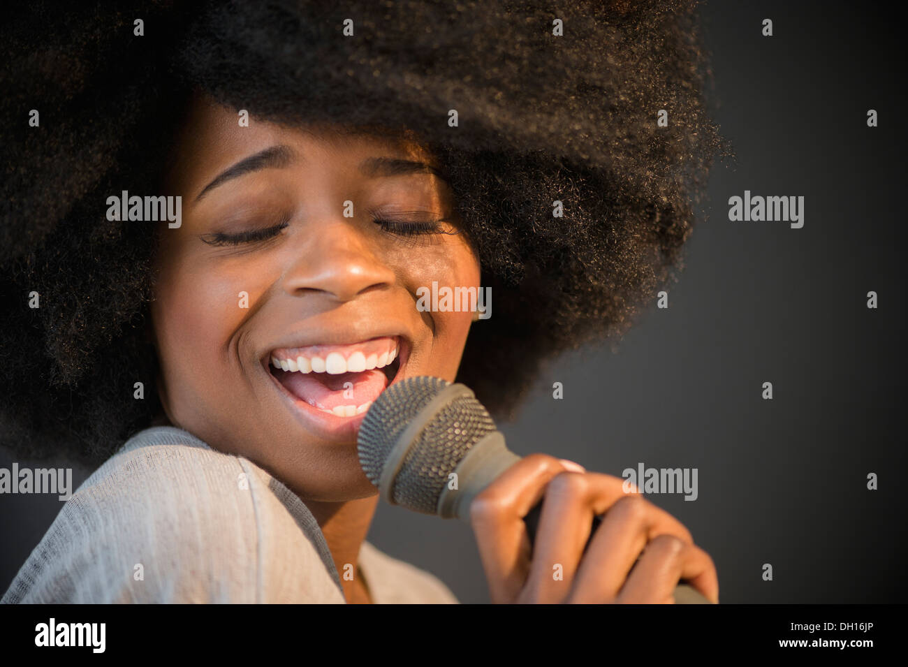 Mixed race woman singing into microphone Stock Photo