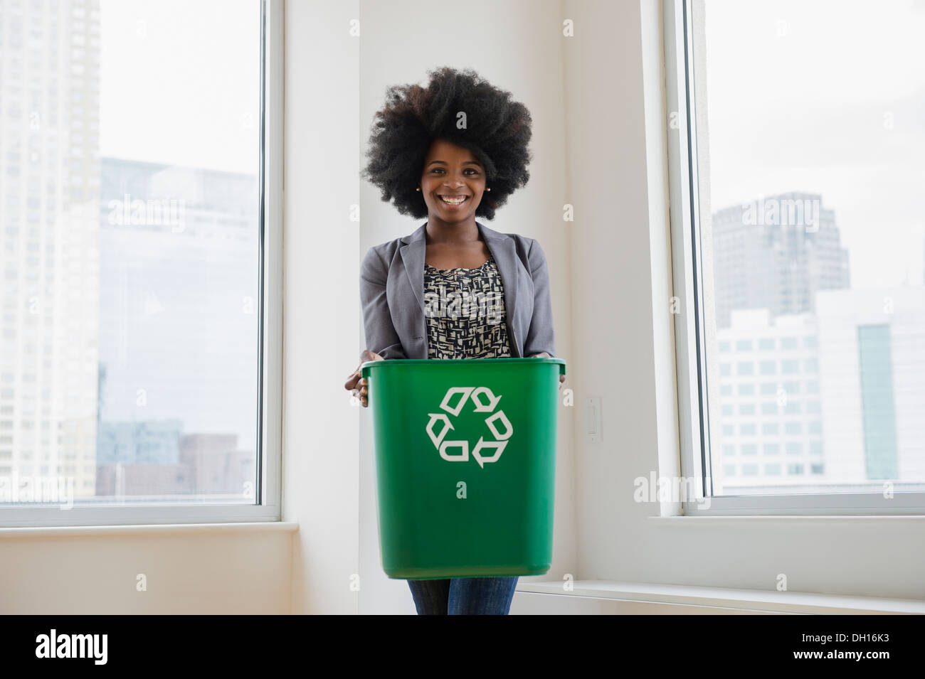 Mixed race businesswoman with recycling bin Stock Photo
