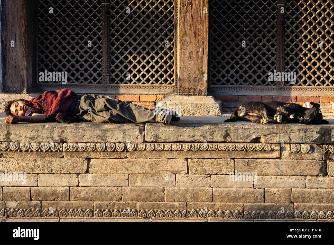 Canine love - Mirror image a boy and his dog sleep in the evening sun, Bhaktapur, Nepal Stock Photo