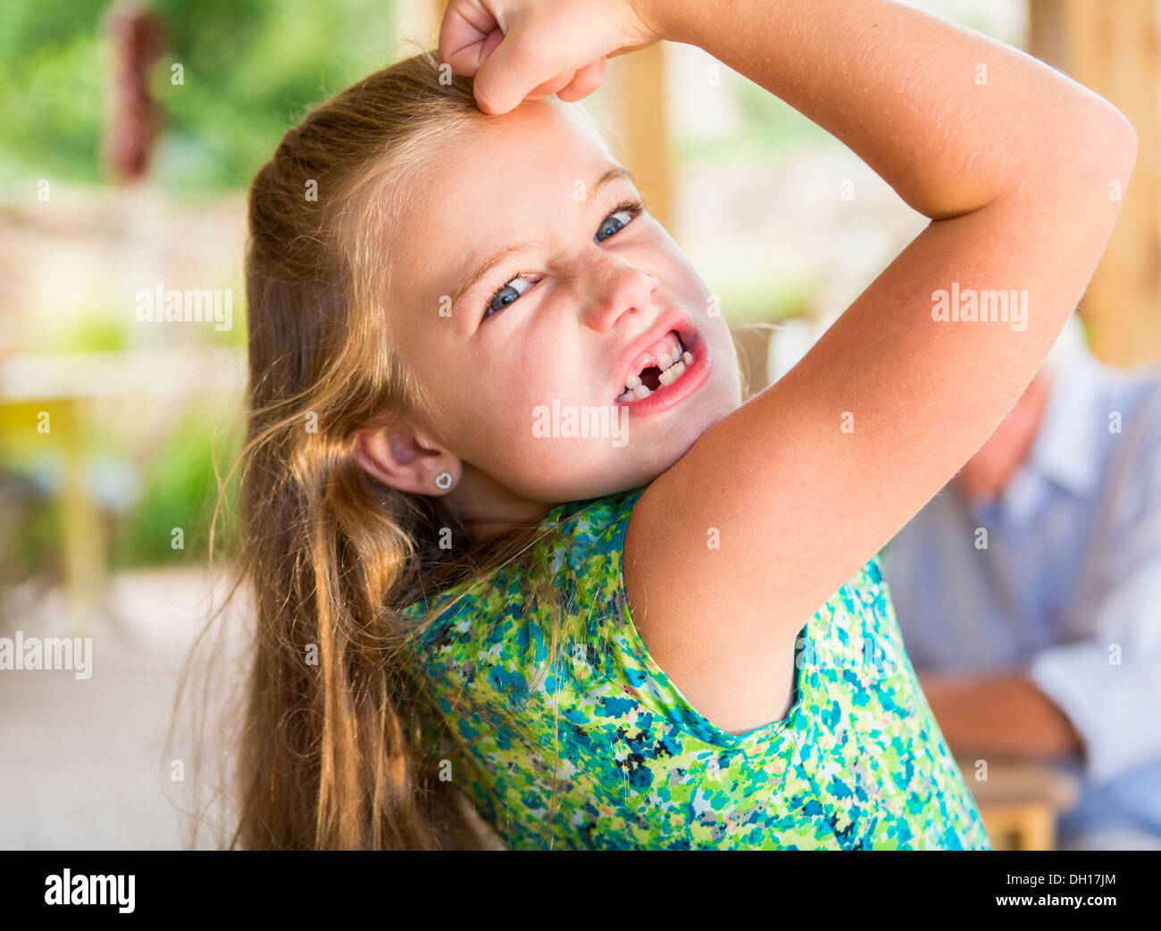 Caucasian girl showing missing teeth and flexing biceps Stock Photo