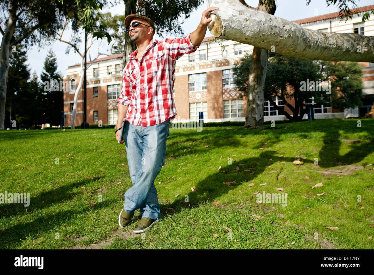 Man leaning against tree branch in park Stock Photo