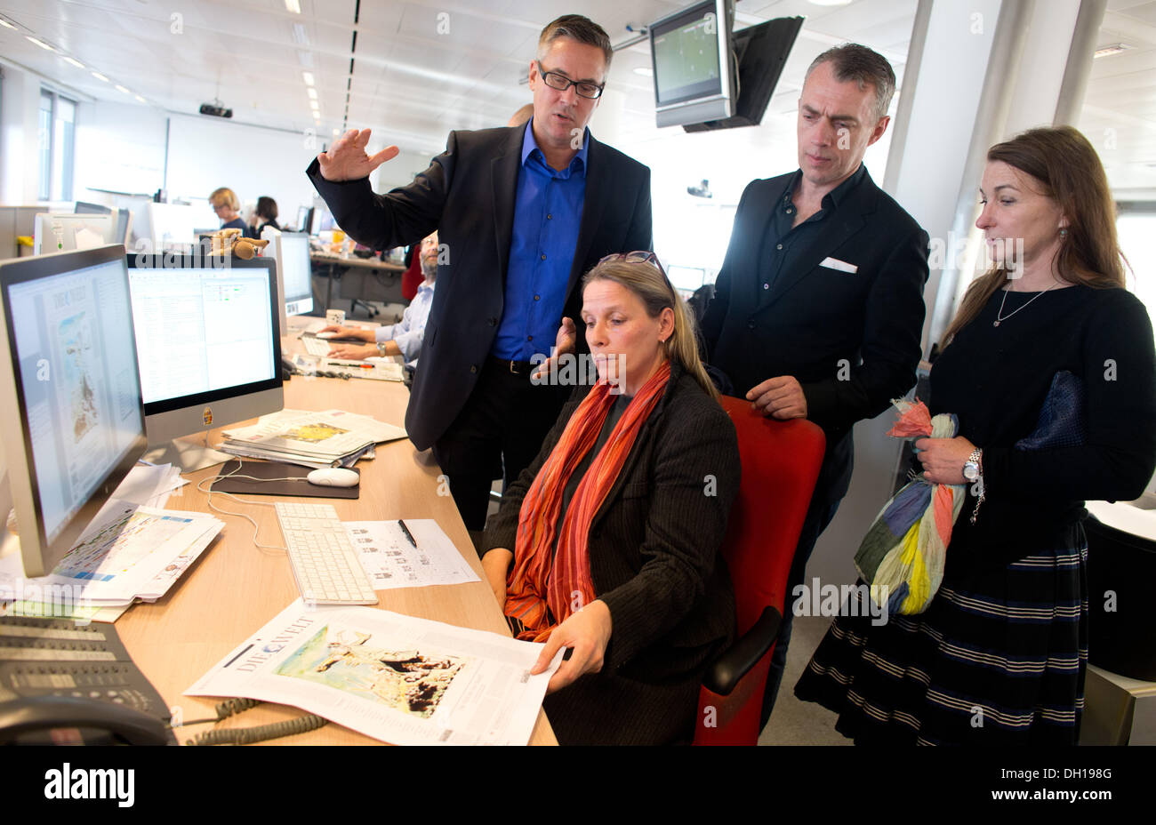 Berlin, Germany. 29th Oct, 2013. The painter Neo Rauch (2-R), Managing Editor, Patricia Plate, chief editor Jan-Eric Peters (L) and Rauch's wife Rosa Loy (R) look at the title page designed by Rauch in the newsroom of the German daily newspaper 'Die Welt' in Berlin, Germany, 29 October 2013. The newspaper with numerous pictures of the contemporary artist will be released on 30 October. Photo: KAY NIETFELD/dpa/Alamy Live News Stock Photo