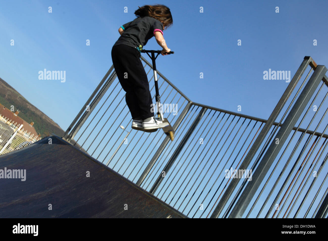 Young Boy riding a scooter, flying off a skate ramp in a Port Tabot skate park. Stock Photo