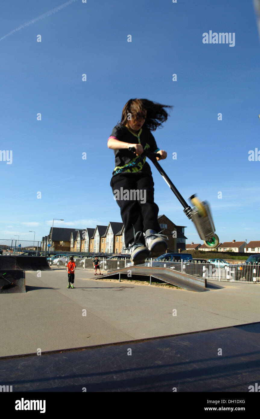 Young Boy riding a scooter, flying off a skate ramp in a Port Tabot skate park. Stock Photo