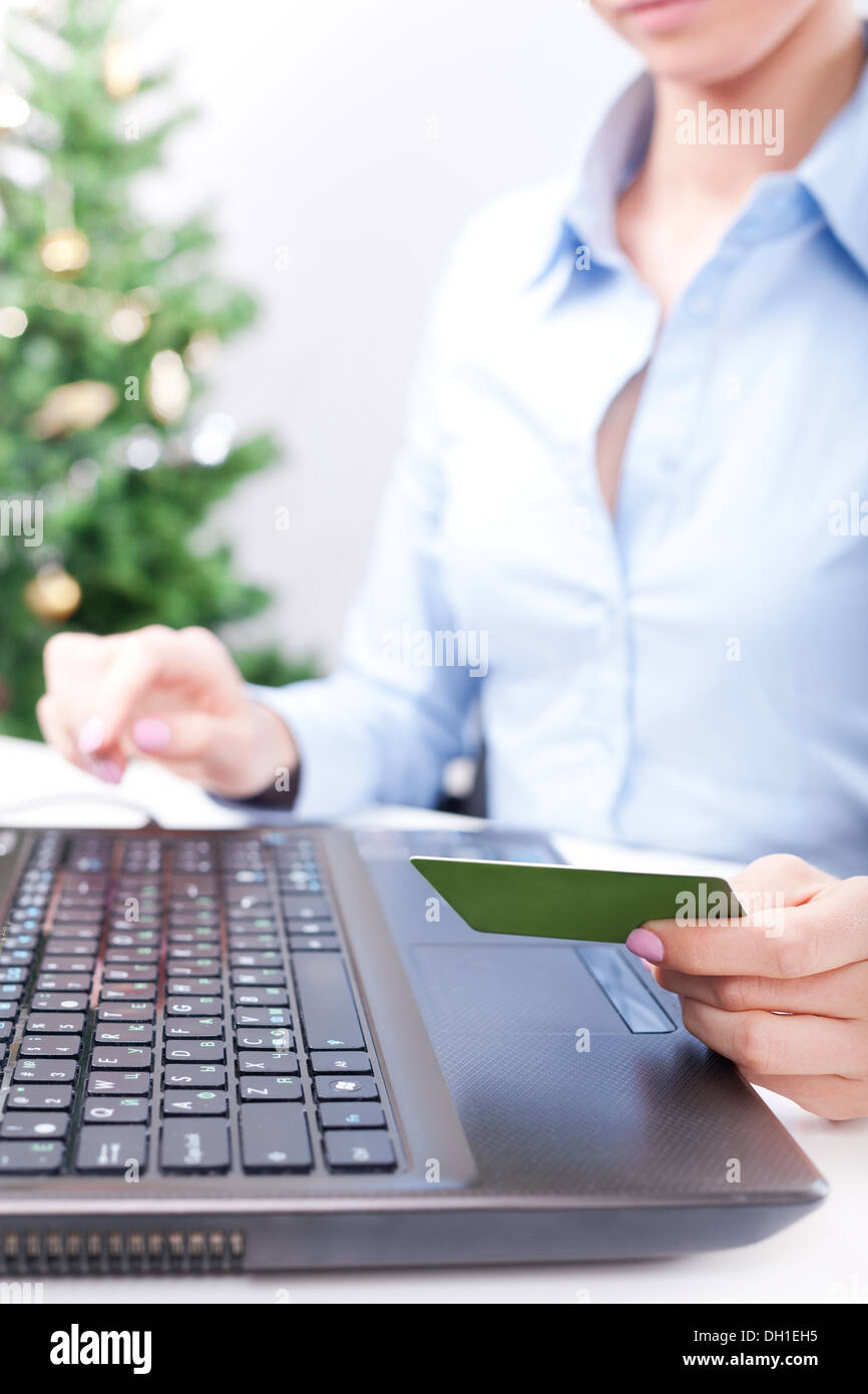 Christmas on-line shopping, woman using credit card for payment, New Year tree on background Stock Photo