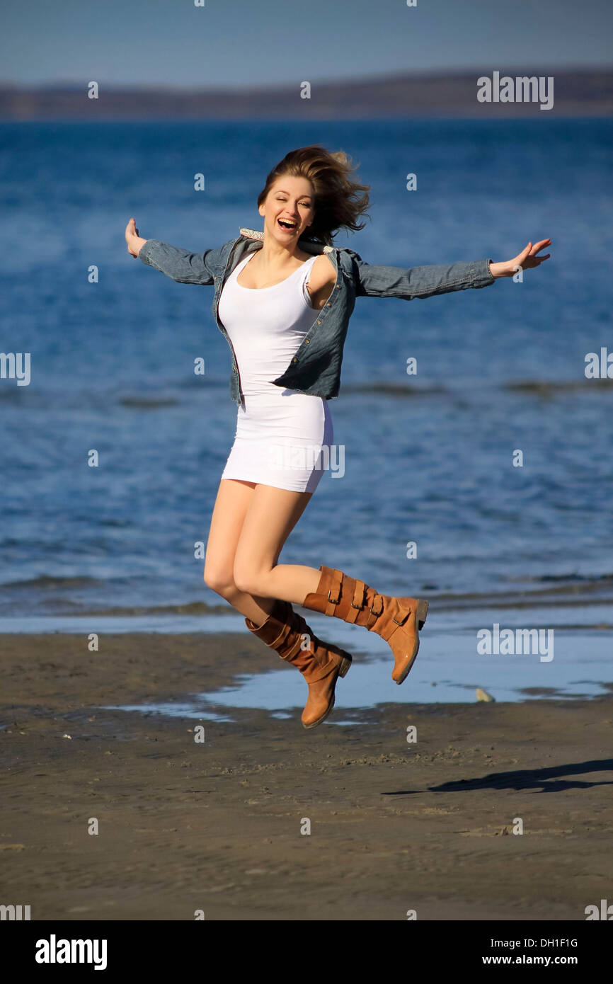 Young woman jumping on beach, arms out, Denmark, Europe Stock Photo