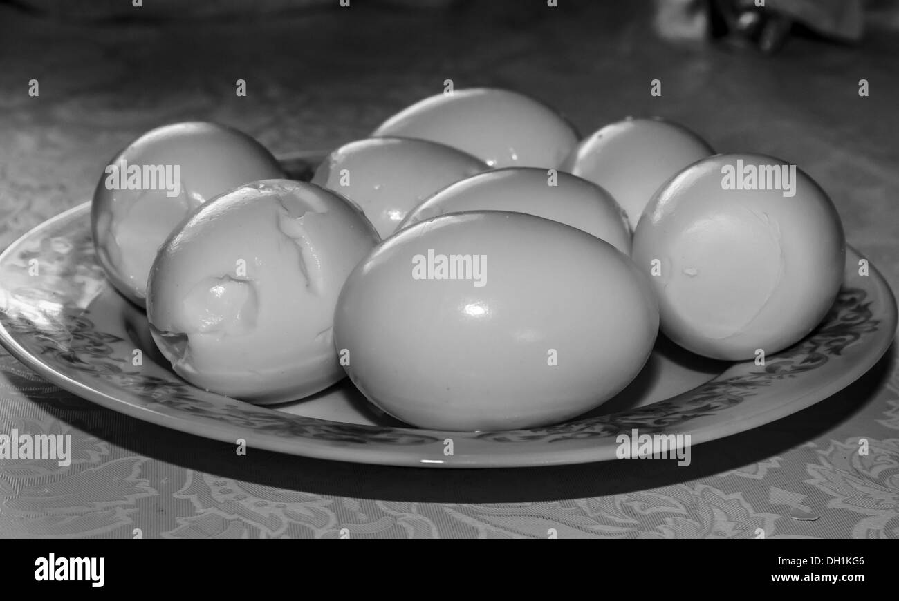 BW photo of several eggs, peeled out of shells, lying on a plate Stock Photo
