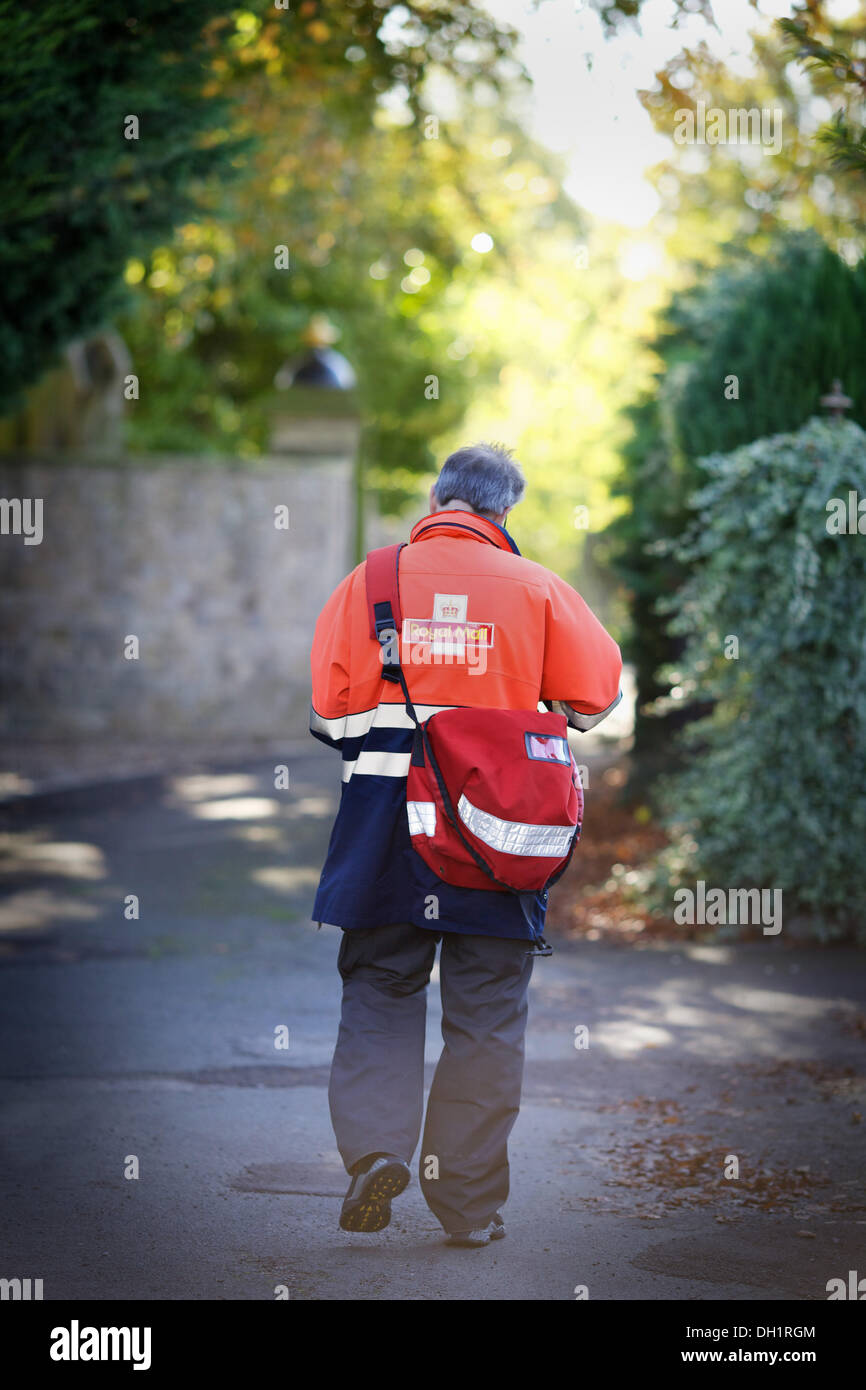 postman walking the street delivering mail Stock Photo